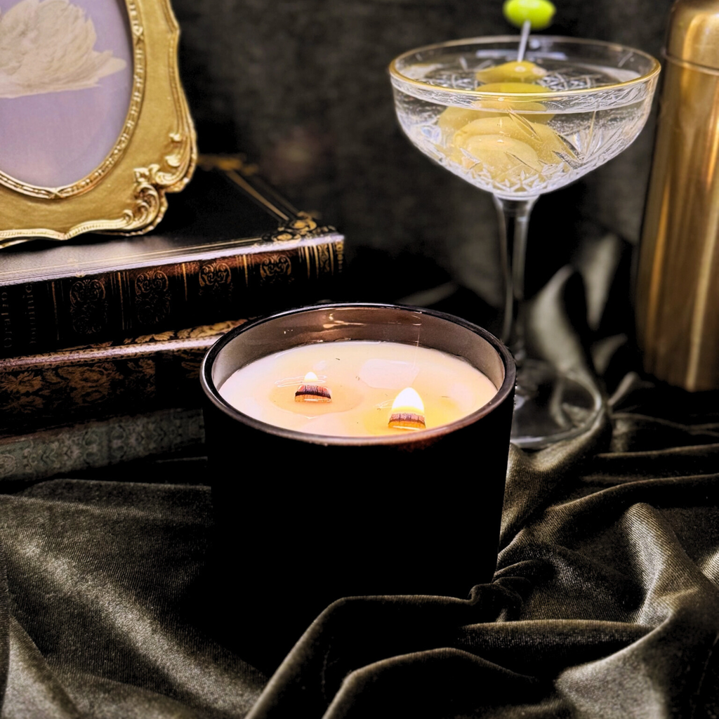 Candle in a black holder with a cocktail and decorative items on a dark fabric background