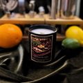 Candle with a label on a dark surface with fruits in the background