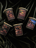 Five candles with scenic labels on a black satin background